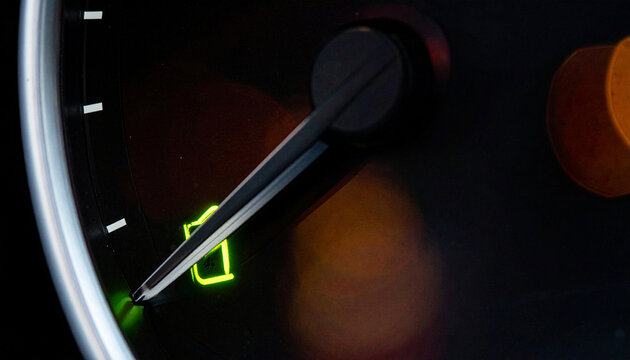 Close-up of a car's fuel gauge indicator light glowing green dashboard instrument panel