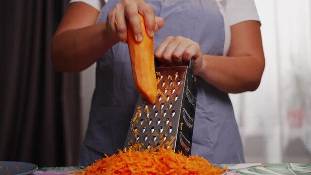 Close-up of female hands grating carrots for homemade healthy food. High quality 4k footage