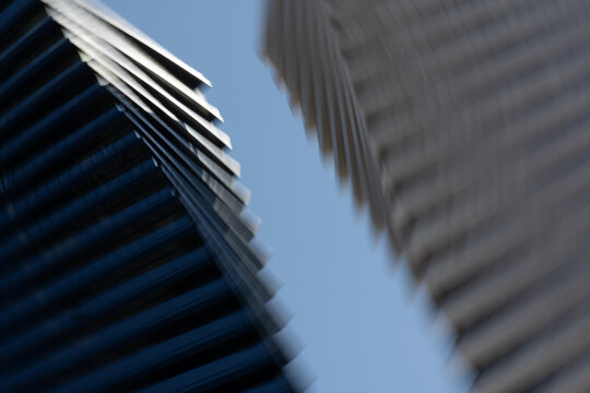 Blurred view of modern city buildings in motion. Abstract urban background representing speed, pressure, stress, and disorientation in fast-paced city life. Minimal composition with copy space.