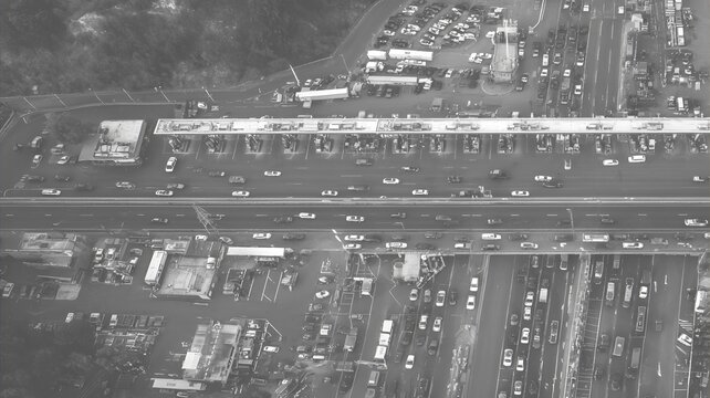 Aerial view of a busy highway toll plaza with heavy traffic and surrounding infrastructure