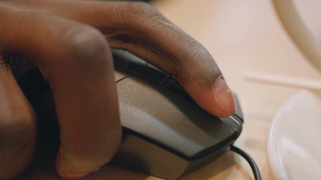 Focused work environment. Developer intensely engaging with computer. Closeup of hand operating mouse with concentration. Detailed view of hand clicking mouse in bright office setting