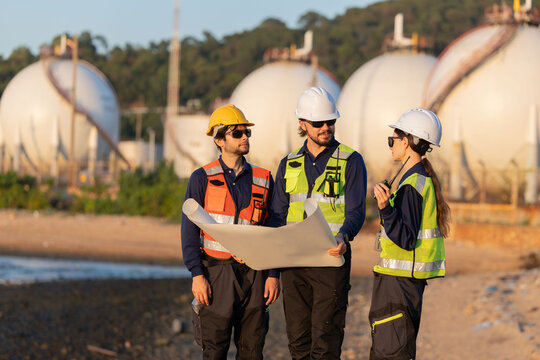 Petroleum engineers having a discussion near oil storage tanks