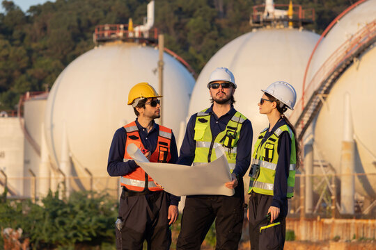 Petroleum engineers having a discussion near oil storage tanks