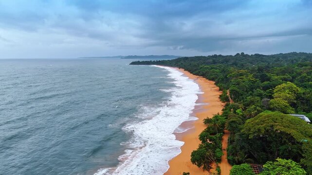 Panama Aerial Coastline With Forest And Ocean Surf. High aerial view of Panama coastline with forest, orange sand, ocean waves, and cloudy sky.