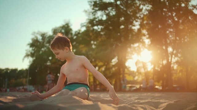 happy kid play with sand and buried on beach or sea shore in summer vacation, smiling boy playing and digging in sand on river beach at sunny day 4k