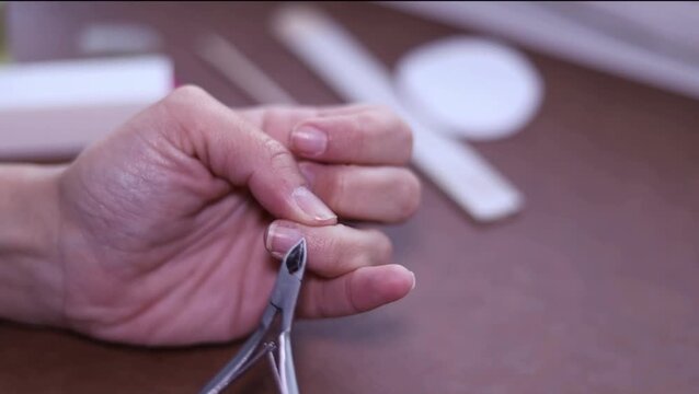 Close-up of person's hand meticulously trimming finger cuticles with nippers for home manicure.