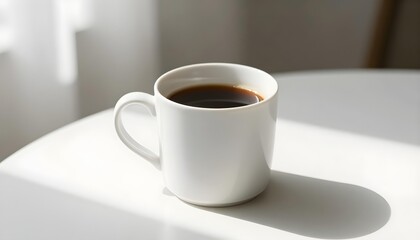 Obraz premium A white mug filled with dark coffee sits on a white table with morning light