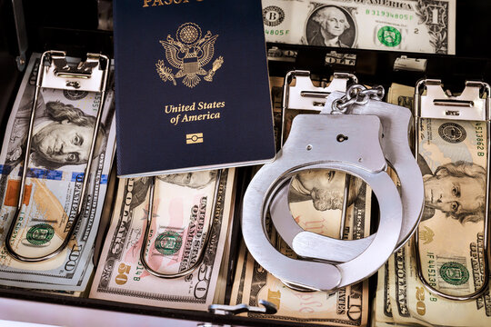 American passport, handcuffs on stacks of dollar cash in banknotes drawer inside police office during legal inquiry.