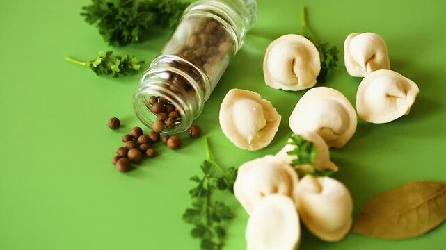 Fresh pasta dumplings with seasoning on green minimal background