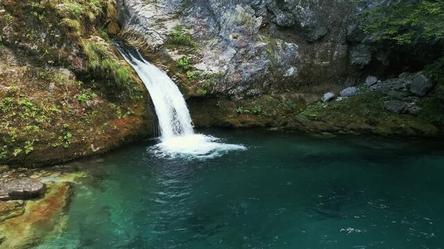 Slow motion drone orbital flight circling the Blue Eye Kaprre waterfall and turquoise pool in the Albanian Alps near Theth. Majestic nature and crystal clear water