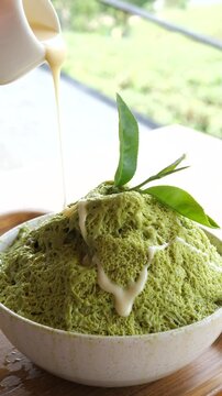 Cinematic action shot of pouring sweet condensed milk from a pitcher over fluffy matcha green tea shaved ice (Bingsu), mouth-watering summer dessert