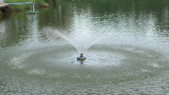 Cinematic shot of a floating water fountain aerator splashing and spraying water in a pond, surface aeration system for water quality and environmental management