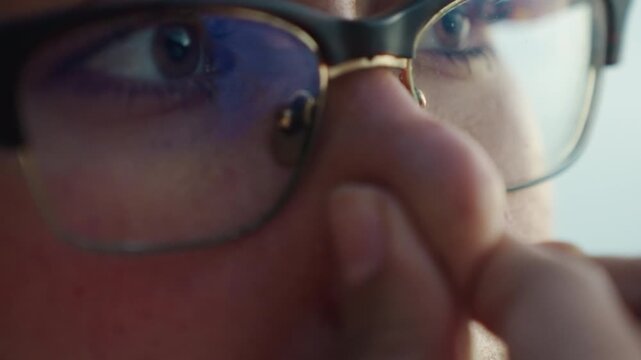Closeup eyes behind glasses looking, contemplative breath and fingertip near nose, reflective lens and ring detail, quiet determination in soft natural light, emotional microexpression and textured