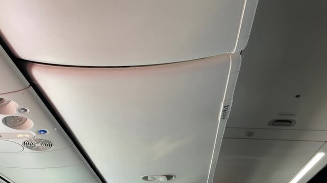 Airplane overhead cabin compartment closed inside passenger aircraft interior with buttons visible