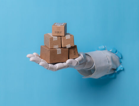 Robotic hand holding stack of cardboard boxes through blue paper hole