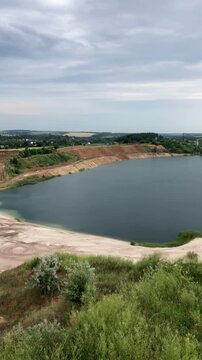 Panoramic view of an industrial sand pit transitioning into a deep blue lake.