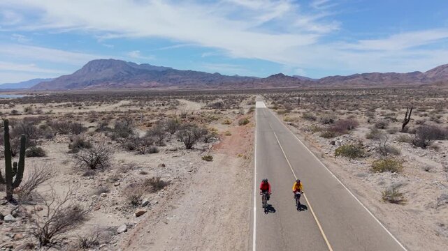 Mature man and woman bike along the road near La Gringa in Bahia De Los Angeles, enjoying the views in Baja California Mexico.