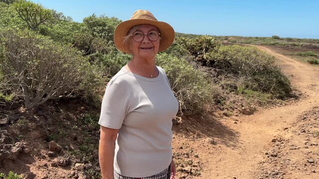 Joyful Senior Woman Enjoys a Sunny Walk on a Scenic Dirt Path in Nature