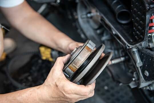 Professional mechanic holding a motorcycle rear clutch pulley assembly for CVT system maintenance.
