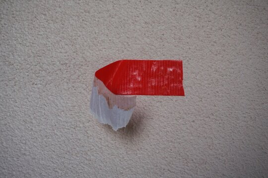 Conceptual Image of Peeling Red Duct Tape on a Textured Wall Surface