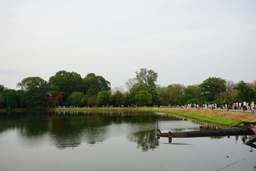 Fototapeta premium Relaxing Atmosphere at Ang Kaew Reservoir, Chiang Mai University with People Strolling Along the Lake