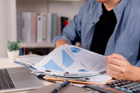 man hands reviewing financial report with pie chart and bar graph on desk. Freelance data analysis, market strategy, home office investment planning and business growth.