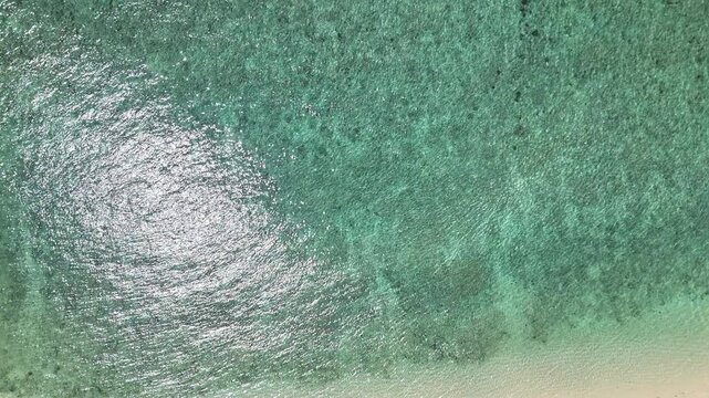 Aerial View of Turquoise Sea Sunlight Reflection on Water Surface with Gentle Waves Creating Serene and Tranquil Atmosphere