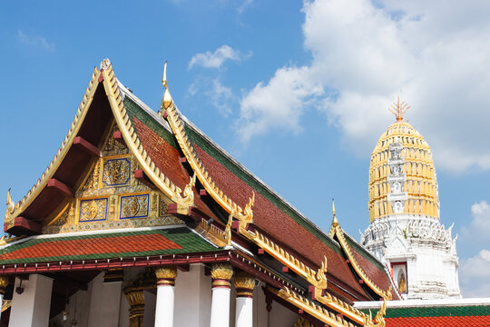 Traditional Thai temple roof and golden prang stupa against a clear blue sky at Wat Phra Si Rattana Mahathat, Phitsanulok, Thailand