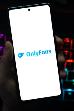 Punta Arenas, Chile &ndash; May 04, 2026: Close-up of a mobile device screen showing the OnlyFans content subscription service logo, held by a user in a dimly lit room with vibrant RGB keyboard lighting