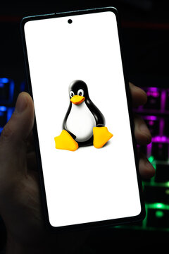 Punta Arenas, Chile &ndash; May 04, 2026: Close-up of a mobile device screen showing the iconic Linux penguin logo, held by a user in a dimly lit room with vibrant RGB keyboard lighting