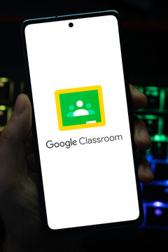 Punta Arenas, Chile &ndash; May 04, 2026: Close-up of a mobile device screen showing the Google Classroom educational platform brand, held by a user in a dimly lit room with vibrant RGB keyboard lighting