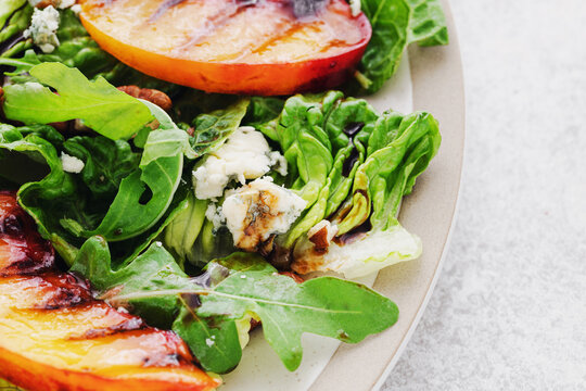 Salad with grilled peach, pecan nuts, blue cheese and arugula