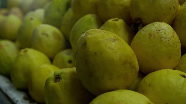 Primer plano de guayabas frescas y maduras apiladas en mercado tradicional - 4K