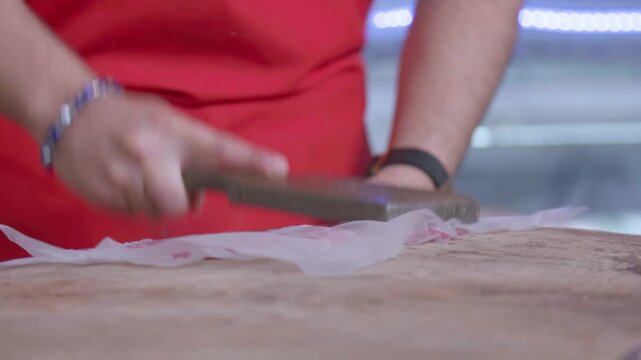 Primer plano de manos de carnicero cortando bistec de res fresco en mercado tradicional - 4K