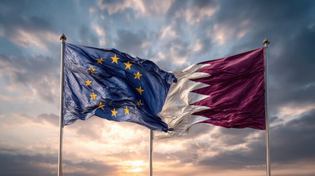 Flags of Qatar and the European Union waving together at sunset over a cloudy sky