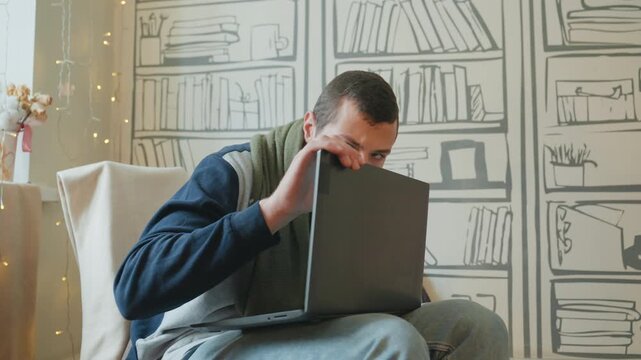 Caucasian man frustrated with laptop, hobbyist confronts malfunctioning hinge and glitching screen in cozy room with patterned bookshelf wall tense gestures, careful inspection with hands