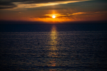 Fototapeta premium A bright sea sunset with a bird-shaped sun in the sky