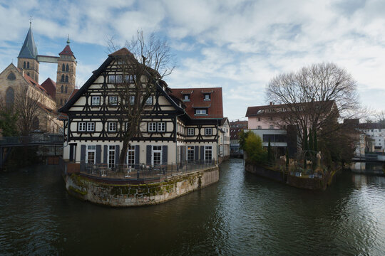 Picturesque half-timbered house on a river canal with St. Dionysius church in Esslingen, Germany