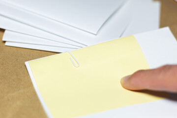 Obraz premium A finger pointing at a blank sticky note on top of a stack of documents; a visual concept of review or pre-marking in a document-handling environment