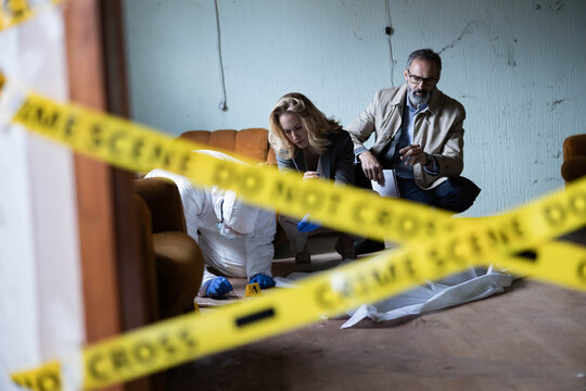 Forensic team and detectives collaborating on an investigation, collecting evidence inside a cordoned-off crime scene
