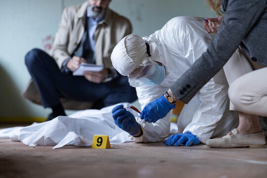 Forensic team examining a crime scene, collecting blood samples and documenting findings during an ongoing investigation
