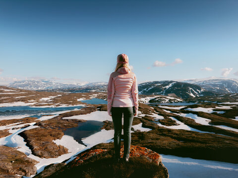Woman traveler enjoying mountains view standing on cliff in Norway, girl hiker climbing solo outdoor explore Lahko park active healthy lifestyle adventure summer vacations harmony with nature freedom