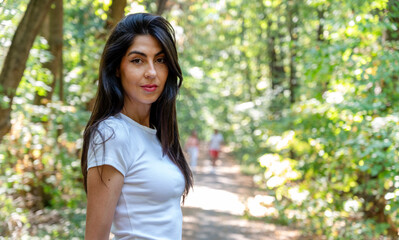 Fototapeta premium Young brunette woman standing in the summer park 