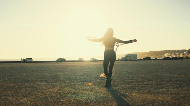 Sunset performance on the beach with a dancer and rope in a coastal city