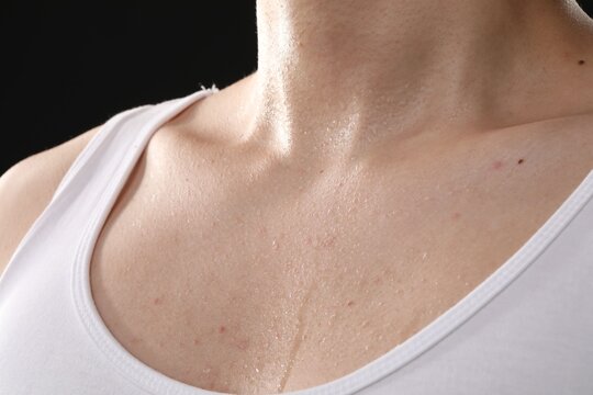 Young guy with sweat on his body against black background, closeup