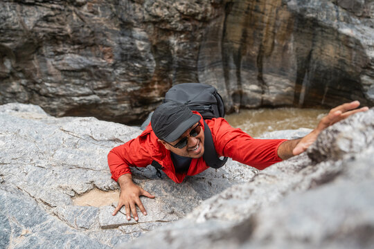 The climber had an accident after falling down the mountain. Hiker climber carefully grips a rock while scaling a steep cliff during a hike in a national park.