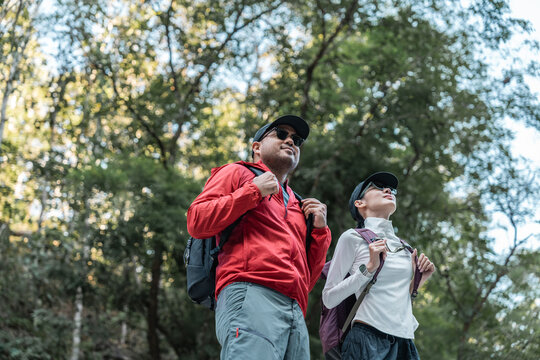 Couple Hiker man and woman climbing rocky mountain to explore cave hill and river enjoying outdoor adventure trekking, and nature travel. Two traveller and nature lover on an exciting hiking journey