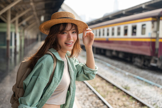 Freedom traveler beautiful woman at terminal train station. Happy tourist travel by train on vacation time holiday weekend trip. Female Backpacker arrival at platform railway.