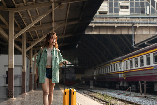 Freedom traveler beautiful woman at terminal train station. Happy tourist travel by train on vacation time holiday weekend trip. Female Backpacker arrival at platform railway.