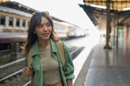 Freedom traveler beautiful woman at terminal train station. Happy tourist travel by train on vacation time holiday weekend trip. Female Backpacker arrival at platform railway.